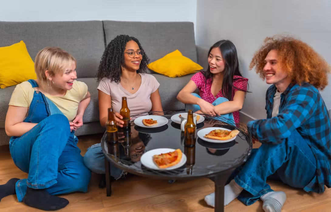 A group of friends relax together, enjoying pizza and drinks in a cozy setting. Their laughter and conversation highlight the joy of simple moments.